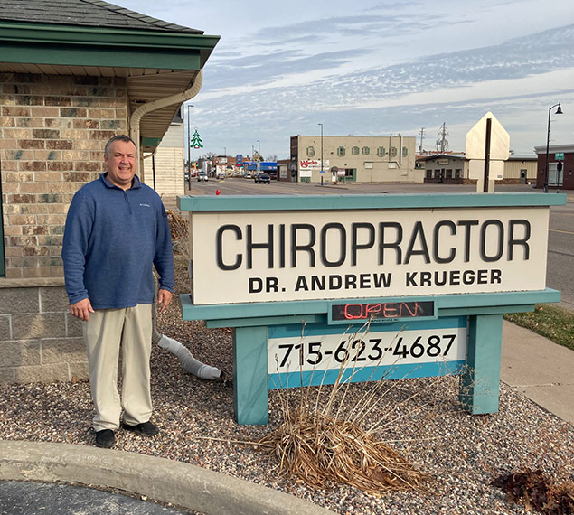 Dr. Andy Krueger stands next to his business sign